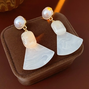 Detail view of geometric pearl earrings with marble resin texture on velvet jewelry box