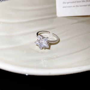 Detail of silver star ring with large zircon stone and pavé setting on white plate