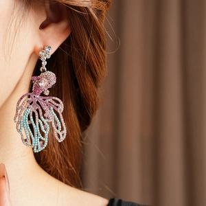 Gros plan d'un mannequin portant de longues boucles d'oreilles poisson en strass vintage