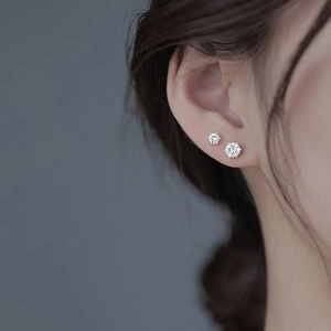 Classic six-prong sterling silver moissanite stud earrings shown on ear for style reference