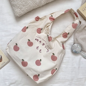 Detail of peach print canvas tote bag with Japanese text on a lifestyle backdrop