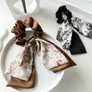 Detail of satin floral scrunchies with long ribbons on a minimalist white tray