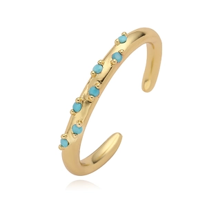 Detail of gold ear cuff featuring a row of seven small round turquoise stones