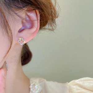 Macro shot of a model wearing a hollow clover stud earring with sparkling diamond pave