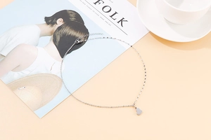 Close-up of a silver heart pendant necklace on a Kinfolk magazine and coffee cup
