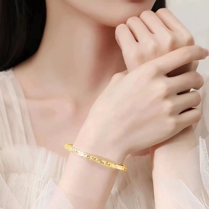 Elegant gold adjustable bangle with glittery sand finish on female model's wrist
