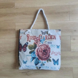 Close-up of vintage canvas tote bag with red rose, butterfly prints and rope handles