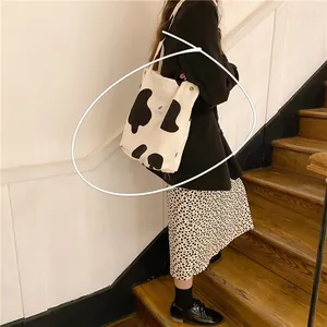 Detalle de un bolso tote de pana con estampado de vaca en blanco y negro y etiqueta tejida