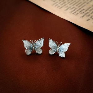 Detail von Schmetterling Ohrsteckern mit blauen Harzeinlagen und Kristallen auf Leder