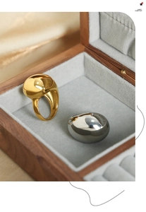 Close-up of pebble-shaped 18K gold and silver rings with high-polish mirror finish