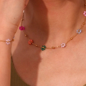 Detail of colorful daisy charms on a gold-plated stainless steel chain necklace on a model
