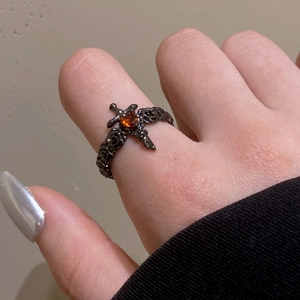 Macro shot of gothic black thorn ring with amber gemstone and silver cross detail