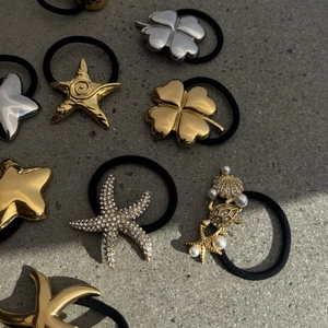 Dettaglio di elastici per capelli con ciondoli oro e argento decorati con perle e strass lucidi