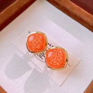 Macro detail of vintage square orange faux stone earrings with elegant gold metallic borders
