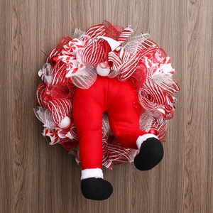 Christmas wreath with Santa legs and striped ribbon on dark wood floor background