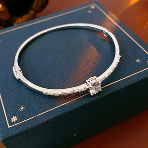 Macro detail of silver bangle featuring a round zircon and baguette cut side stones