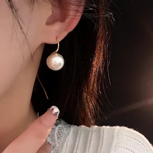 Boucles d'oreilles élégantes en perles dorées portées par un mannequin femme avec style