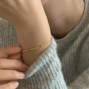 Detailed close-up of a gold snake chain bracelet with small beads on a model wrist