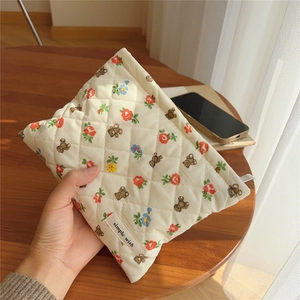 Detail of hand-held quilted fabric bag with cute bear and floral animal print pattern