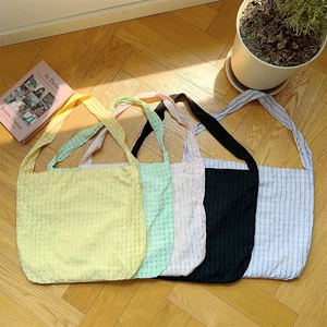 Sélection de cinq sacs cabas en toile à carreaux de couleurs acidulées sur parquet