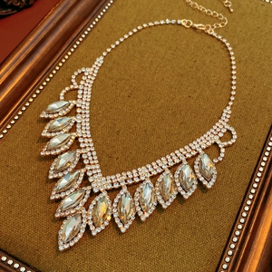 Macro view of gold V-shaped necklace with rhinestones on a vintage velvet display