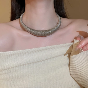 Close-up of chunky silver braided collar necklace featuring thick woven metal texture