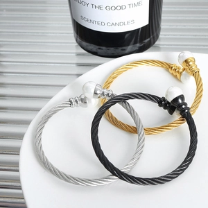 Three-piece cable wire bracelet set in gold, silver, and black with faux pearl tips