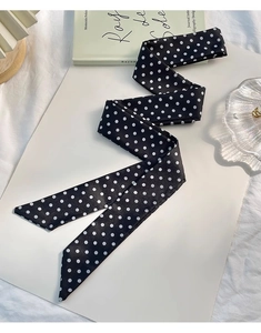 Détail d'un foulard en soie noir à pois blancs plié avec élégance dans un style français