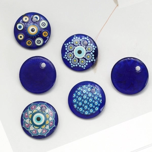Flat lay of seven blue glass evil eye pendants with various mandala patterns for DIY jewelry