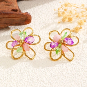 Close-up of golden hollow flower earrings with purple and green crushed stone inlay