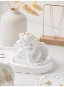 Detailed view of white angel sculpture display stand with pearl bracelet and jewelry