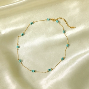 Detail of gold chain necklace with turquoise beads on satin fabric with lobster clasp