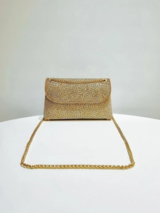 Detailed view of luxury gold rhinestone handbag with spiral crystal patterns and metal chain
