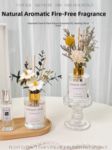 Detailed view of dried flower reed diffusers with glass bottles and gold caps on a table