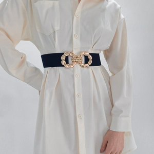 Close-up of black elastic waist belt with large interlocking gold metal buckle on model