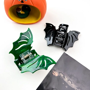 Close-up of glittery green and glossy black bat hair claws for Halloween styling