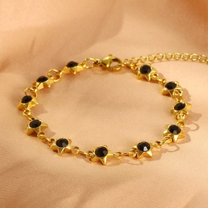 Elegant gold star link bracelet with black zircon stones on luxury silk background