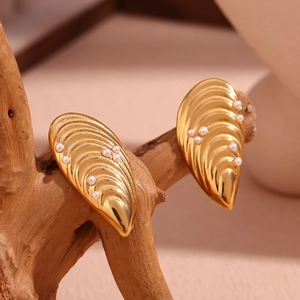Détail de boucles d'oreilles moule en or 18 carats avec petites perles blanches sur bois