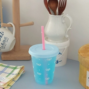 Blue plastic sippy cup with pink straw on a blue counter in a cozy kitchen setting