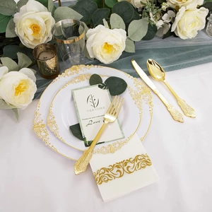 Detail of luxury white and gold plastic dinnerware set with ornate napkins for parties
