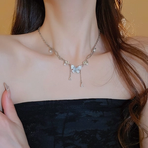 Dettaglio della collana a farfalla argentata con frange e perle sul collo della modella