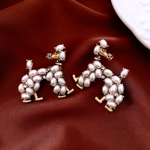 Detail view of poodle earrings with white pearls and crystals on red satin fabric