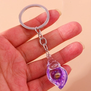Close-up of a hand holding a glowing purple conch keychain with internal seashell detail