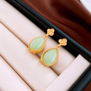 Detailed close-up of water drop earrings with green resin stone and gold cloud motifs