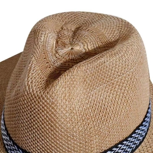 Close-up of the woven straw texture and black and white geometric band on a men's sun hat