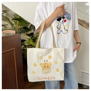 Detail of canvas tote bag showing yellow cartoon giraffe print and woven handle straps