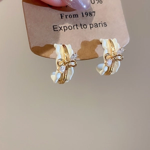 Macro view of 18k gold plated bow stud earrings with clear zircon stones and silver needle