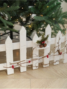 Detail of white wooden Christmas fence with pine cones, berries and snow texture