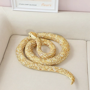 Realistic yellow coiled snake plush toy with scale pattern on a warm beige sofa