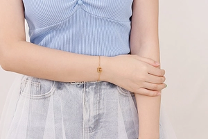 Detail of elegant gold-toned chain bracelet featuring a sparkling CD initial pendant